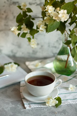 Obraz na płótnie Canvas a Cup of tea and Jasmine flowers on the table on a spring morning
