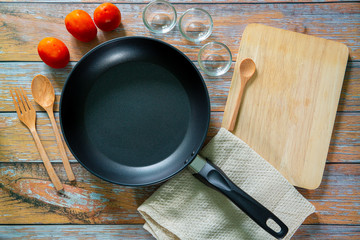 Search by image Cast iron pan and other kitchen utensils on a dark brown aged background, top view 