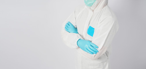 Man is wearing PPE suite and doctor mask or face mask.He is standing and fold one's arms over the chest on white background.