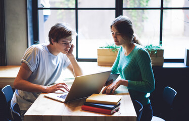 Clever male and female students making research of information for university course work during e learning on laptop device, smart hipsters spending time in university campus for studying via netbook