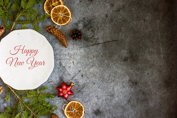 Christmas composition with a white plate, fir branches, cones, Christmas decorations on a dark blue background, top view, copy space, flat lay.Christmas background, vertical background