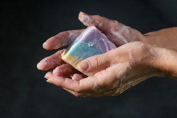 Woman washing hands with natural colorful soap bar.
