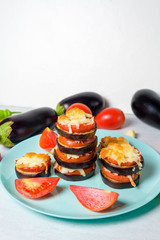 cooking homemade vegan pizza with eggplant on a bite, tomatoes, peppers, mozzarella on a blue plate. eggplant piled up on a light background