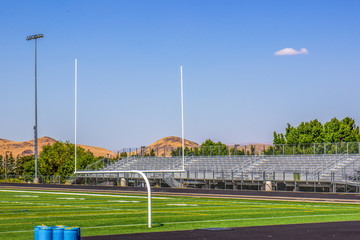 Fototapeta na wymiar Goal Post & Bleachers At School Football Field