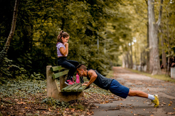 Naklejka na ściany i meble Young man and girl are training in the park