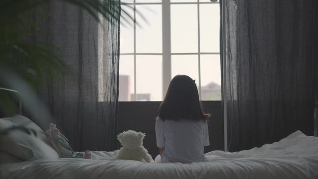 A little sick girl sits on the bed and hugs a soft toy; drip near