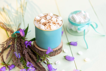 Hot cappuccino with marshmallows and foam in a light blue Cup with flowers.
