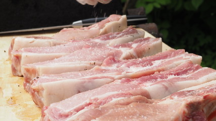 the cook sprinkles the pork steaks with pepper and salt. cooking meat. the marinating pork