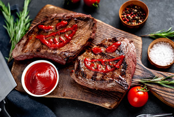 Two grilled beef monster steaks with spices for halloween on stone background