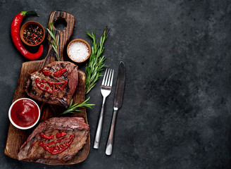  Two grilled beef monster steaks with spices for halloween on stone background with copy space for...