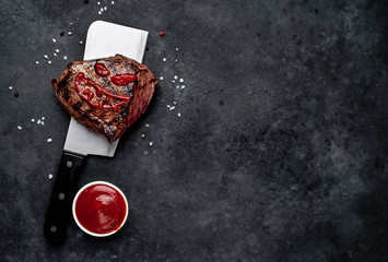 Grilled beef steak with spices on a butcher's knife for Halloween on stone background with copy space for your text