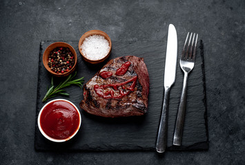 grilled beef steak with spices, knife and fork for halloween on stone background