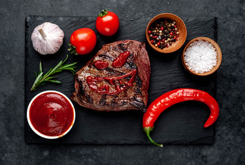 Grilled beef monster steak with spices for halloween on stone background