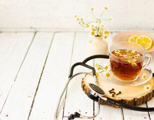 Decoction of chamomile, dried flower in flower tea and a phonendoscope, sliced lemon on a white...