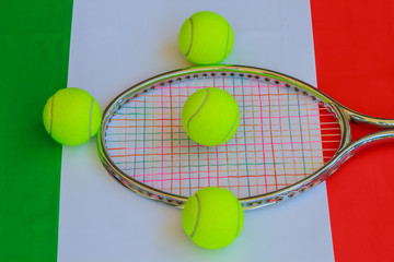 italian tennis / Tennis racket in metal with colored ropes and yellow tennis balls with the italian flag in the background