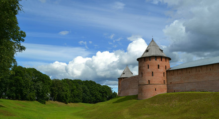 Fototapeta na wymiar Towers and walls of ancient Great Novgorod Kremlin with some clouds in light blue sky in summer day. Veliky Novgorod, Russia. Historical travelling. Panoramic view 