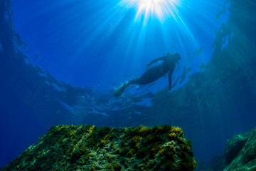 a scuba diver swims  above a Mediterranean seabed