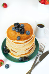 stack of pancakes with syrup and berries
