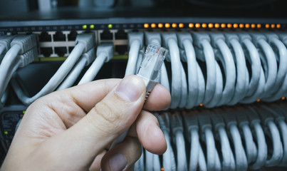 Man holding an ethernet cable ready for connection into the network switch.