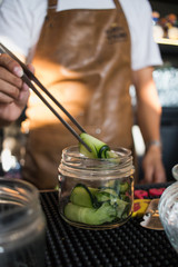 Bartender sosteniendo rollito de pepino para decorar bebida 