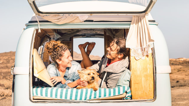 Hipster people with cute dog traveling together on vintage minivan - Wanderlust and life inspiration concept with hippie couple on mini van adventure trip - Bright warm filter