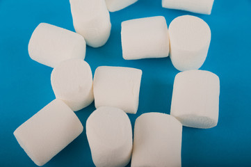 Marshmallows in the shape of a heart on a blue background close-up and copy space. Marshmallow pattern top view on a blue background.