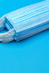 Stack of Disposable blue medical face masks on blue background