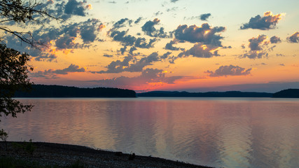 Fototapeta na wymiar sun rising into clouds over lake and mountains