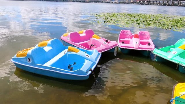 Pier with lot of water catamarans. Four seat water bicycles at dock. River or lake entertainment in downtown.