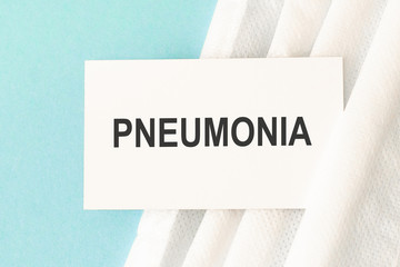 Word pneumonia with medical mask on a blue background. Preventive Medicine