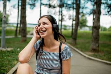 Smiling girl listening music in the park  