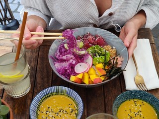 Woman eating tasty colorful healthy natural organic vegetarian Hawaiian poke bowl using asian...