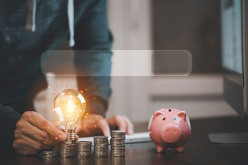 Businessman hand holding light bulb on coins stack on the wooden table , Saving ideas and investment budget, Creative ideas concept of saving money  concept, Copy space