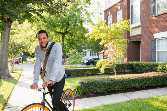 Mixed race man on bicycle on suburban sidewalk