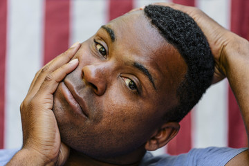 Close up of concerned Black man  in front of American flag