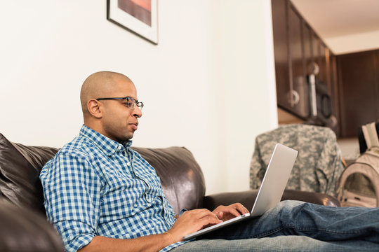 Mixed race man using laptop on sofa in living room
