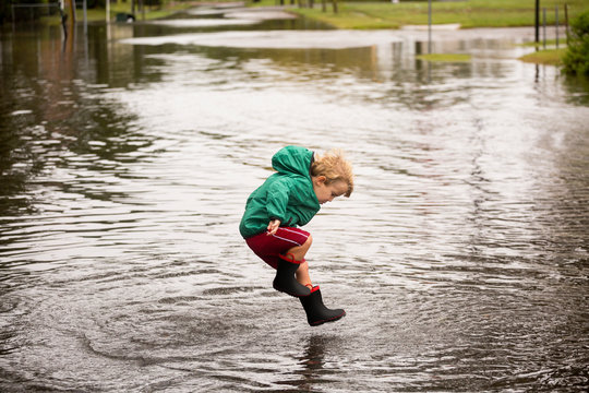 Caucasian boy jumping in puddle