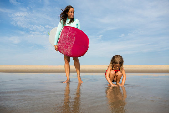 Mother and daughter playing in waves on beach