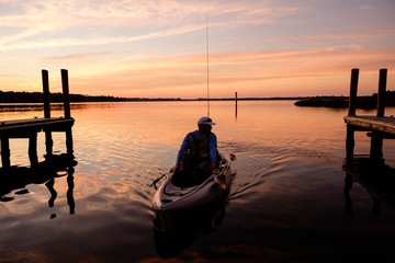 Caucasian man on kayak near dock at sunset