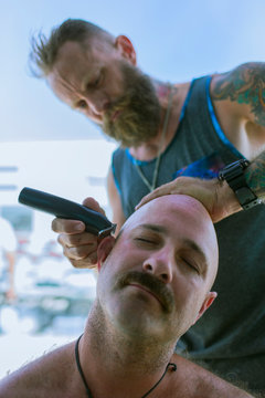 Man Shaving Head Of Friend