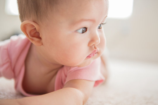 Mixed race baby girl laying on carpet