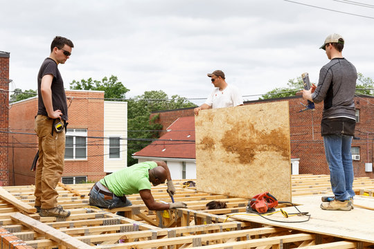 Volunteers Working On The Roof At Construction Site