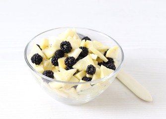 Salad of fresh apples and blackberries in a bowl on a light background