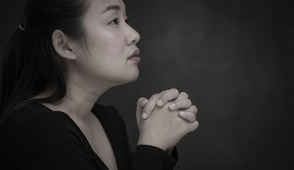 Asian face woman praying and worship to GOD Using hands to pray in religious beliefs and worship christian in the church or in general locations in  White and Black background