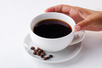 women's hands hold a white coffee mug on a white background.