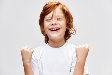 Cheerful redhead child white t-shirt smile Studio gray isolated 