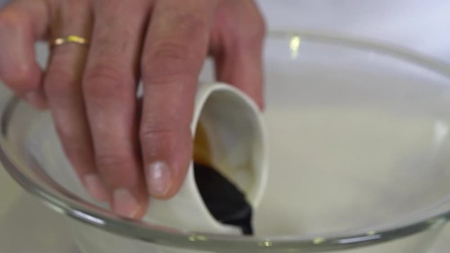 Man pouring soy sauce into glass bowl.  Close up shot