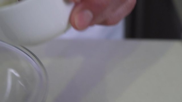 Chef scooping dijon mustard into glass bowl