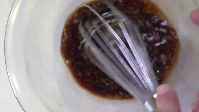 Whisking marinade mixture in glass bowl, vortex movement
