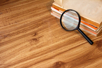 MESA DE MADERA CON LIBROS ANTIGUOS Y LUPA